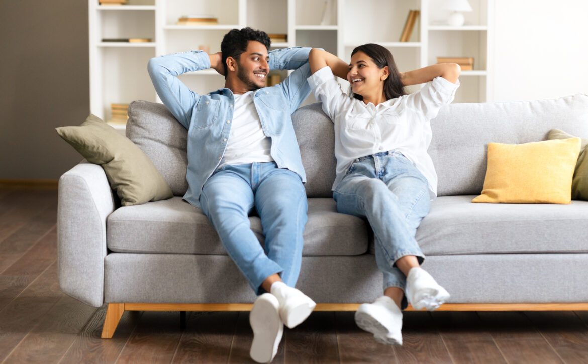 Cheerful Indian couple enjoying a moment on a couch in a cozy living room