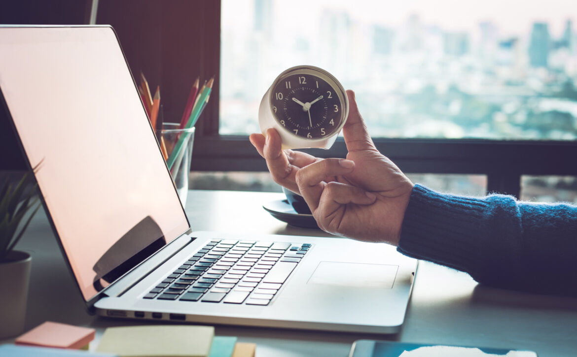 Business concepts with businessman holding clock on computer laptop.For investment analysis,Waiting to sucess