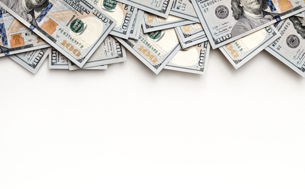 US paper currency with close-up details of one hundred dollar bills. Top view layout with negative space for financial concepts. Banknotes positioned at the top, leaving room for text.