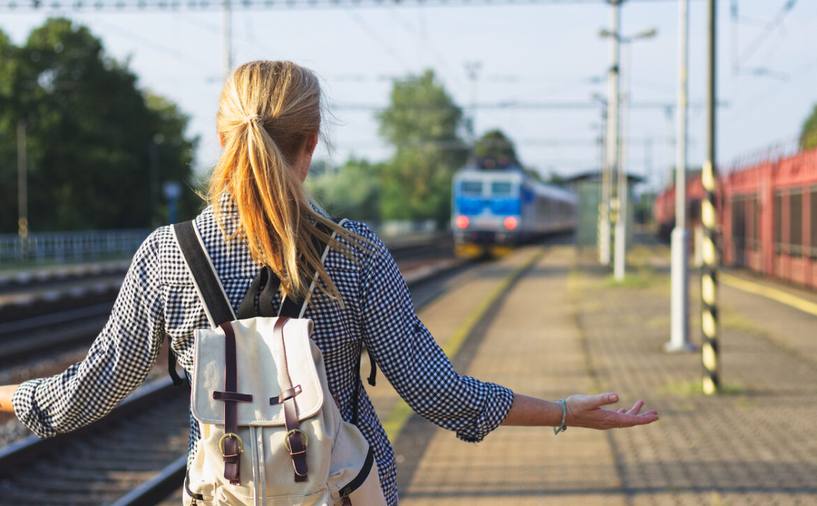 Woman standing on railroad station and looking to leaving train. Traveler is worried, because she missed a train