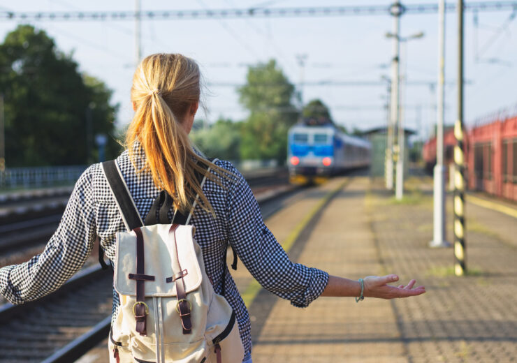 Woman standing on railroad station and looking to leaving train. Traveler is worried, because she missed a train