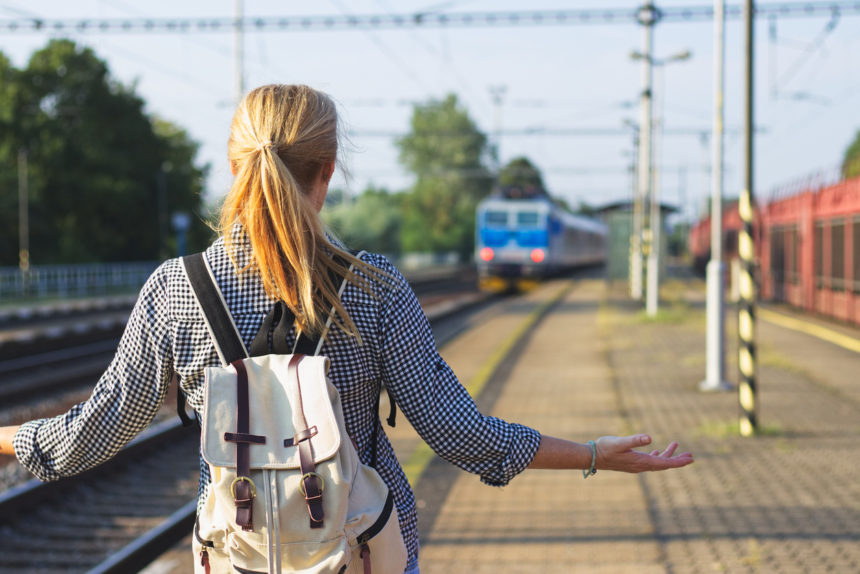Woman standing on railroad station and looking to leaving train. Traveler is worried, because she missed a train