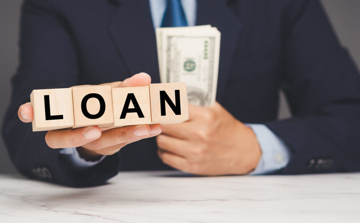 Businessman holding loan blocks and cash, representing financial borrowing and banking concept.