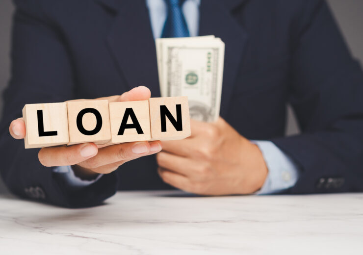 Businessman holding loan blocks and cash, representing financial borrowing and banking concept.