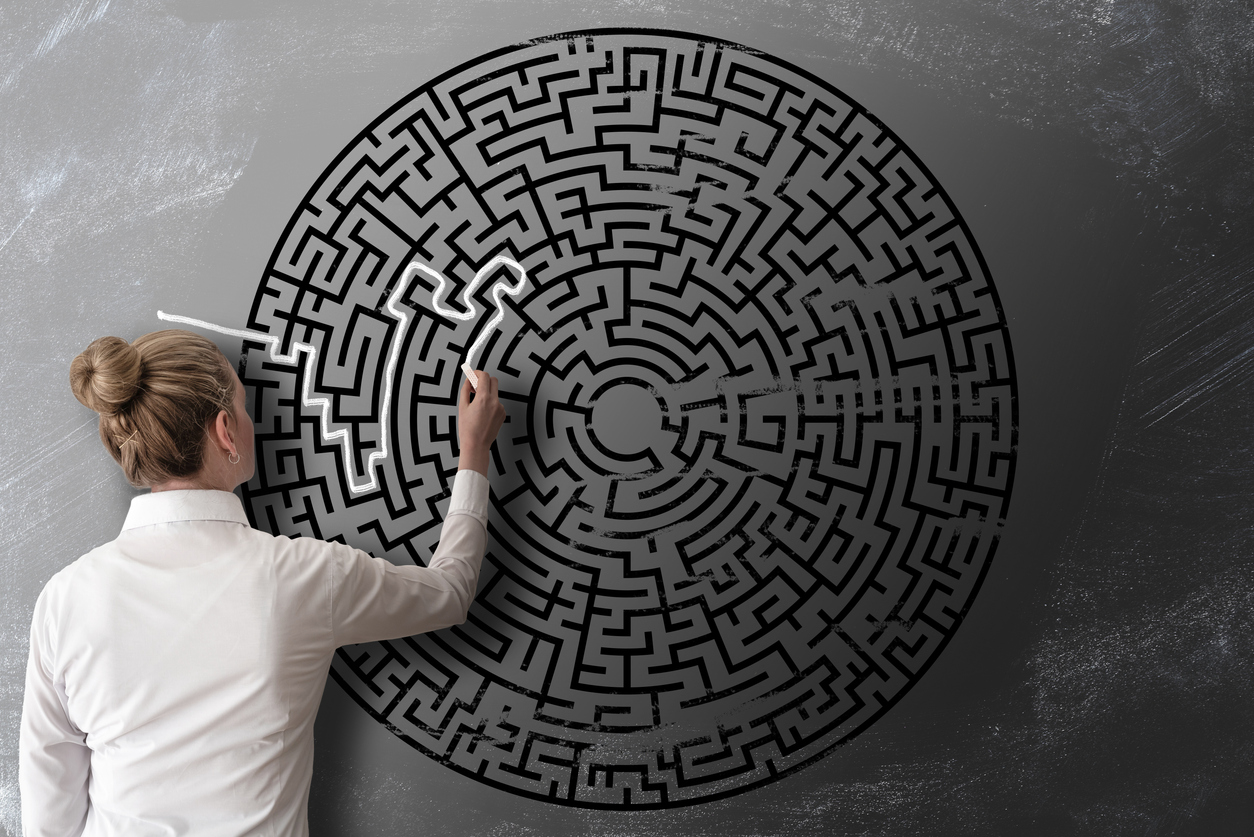 woman trying to find way through chalk drawing of maze on blackboard challenge concept