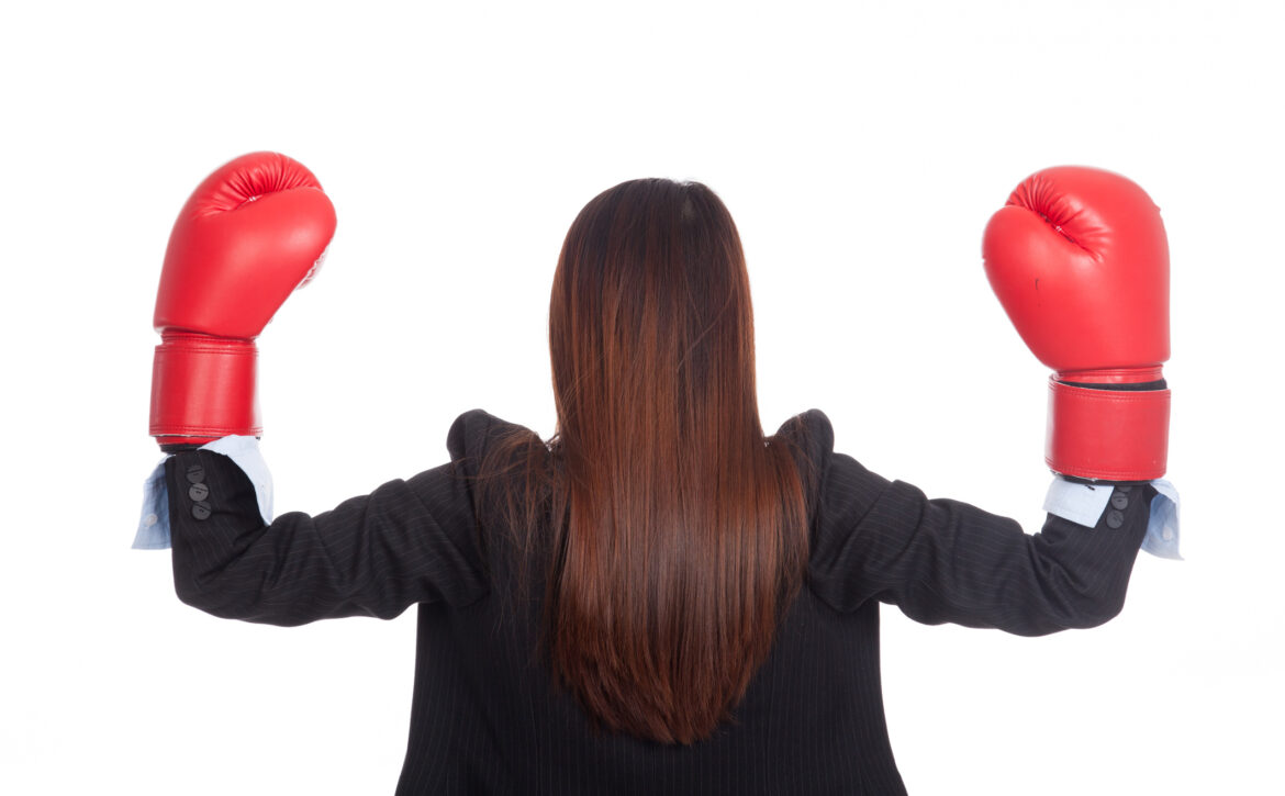 Back of young Asian businesswoman with boxing glove
