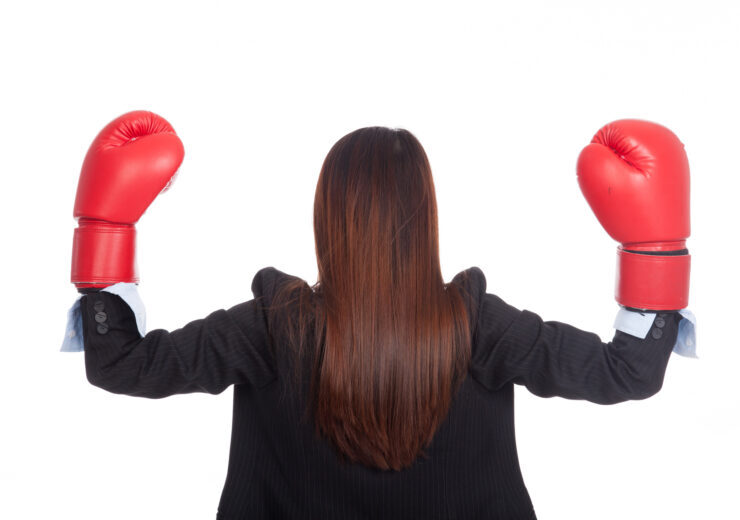 Back of young Asian businesswoman with boxing glove
