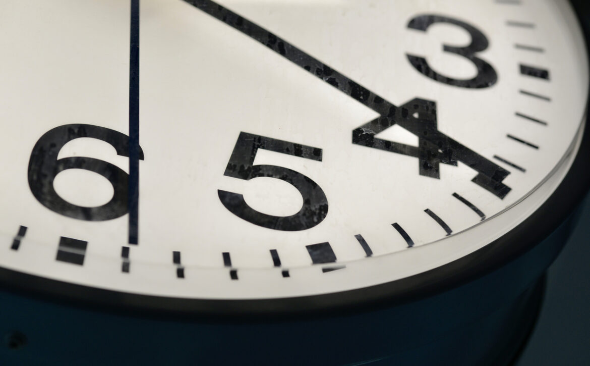 A close-up view of a vintage analog clock showing the time with bold black numbers