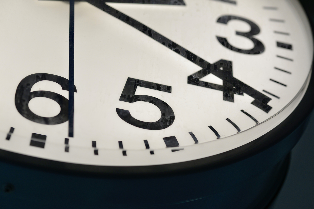 A close-up view of a vintage analog clock showing the time with bold black numbers