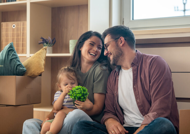 Young couple with their daughter happily moving into their new apartment after buying it with a bank loan. First-time homeowners enjoying freedom after years of renting, smiling in their new home.