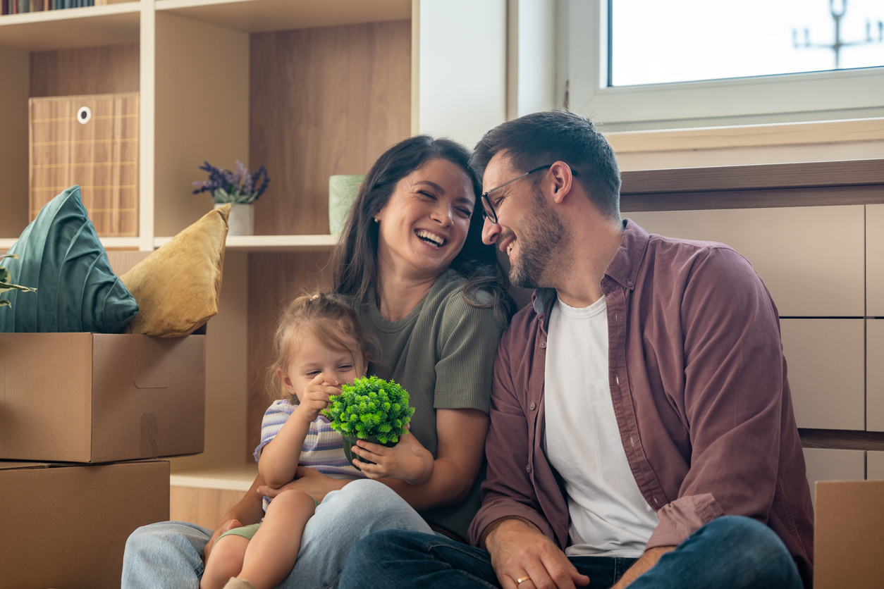 Young couple with their daughter happily moving into their new apartment after buying it with a bank loan. First-time homeowners enjoying freedom after years of renting, smiling in their new home.