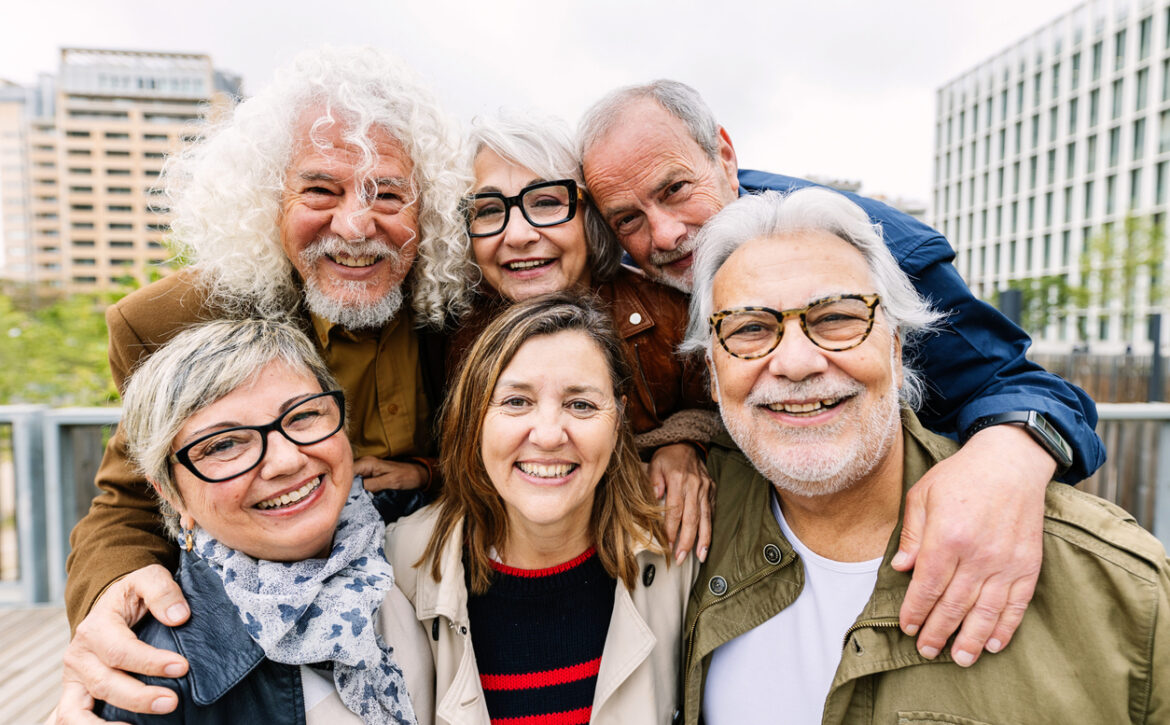 Portrait of happy diverse senior friends standing together at city