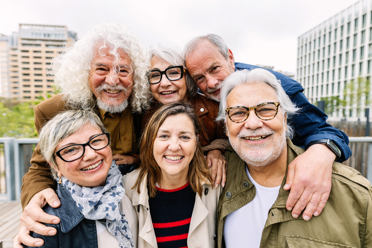 Portrait of happy diverse senior friends standing together at city