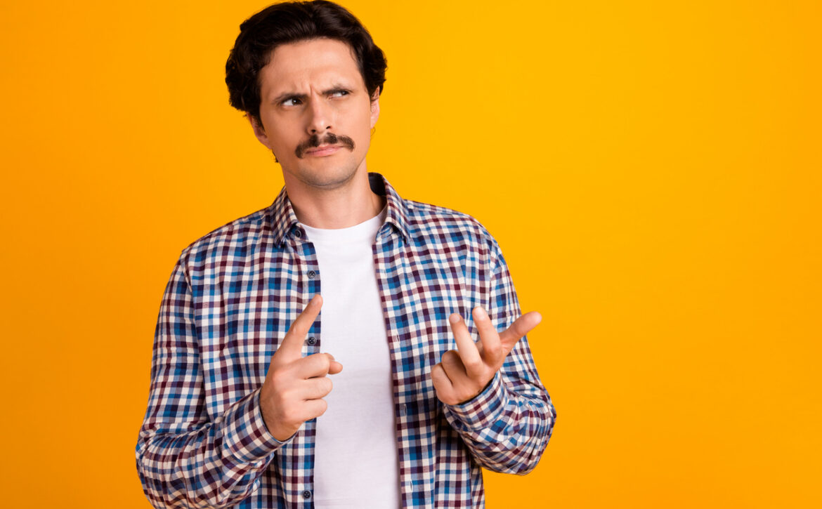 Photo of handsome unsure young guy fingers count math problem look empty space wear trendy plaid look isolated on yellow color background