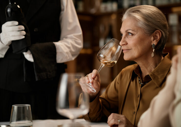 Senior Caucasian Woman Smelling Wine While Sitting at Table in Restaurant