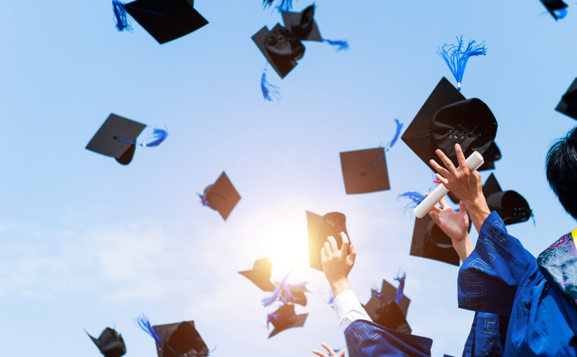 Graduating students hands throwing graduation caps in the air