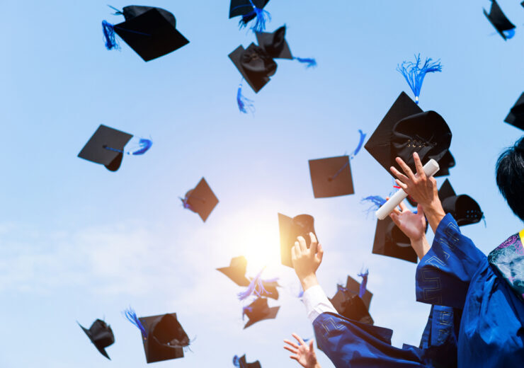 Graduating students hands throwing graduation caps in the air