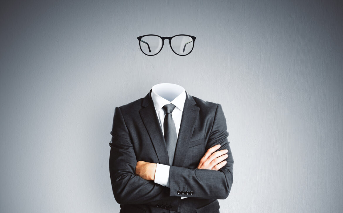 Headless invisible businessman in suit with folded arms and abstract glasses standing on gray wall background. Business and secret concept.