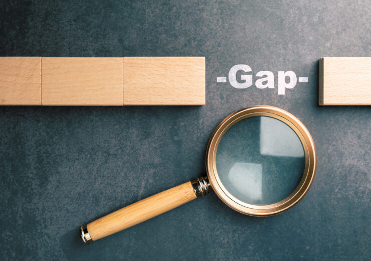 Gap analysis concept with magnifying glass examining missing block