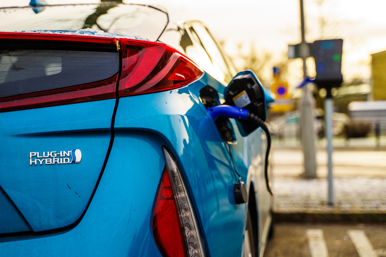 Electric plug in hybrid car parked on street parking lot for charging
